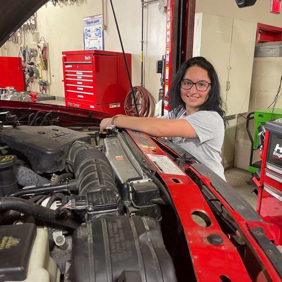 Female auto tech student works under the hood