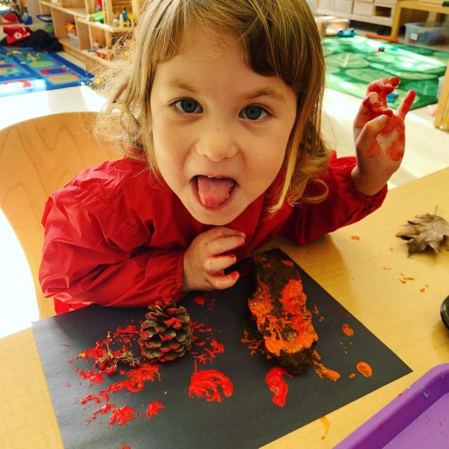 Little girl in early childhood makes face while doing artwork