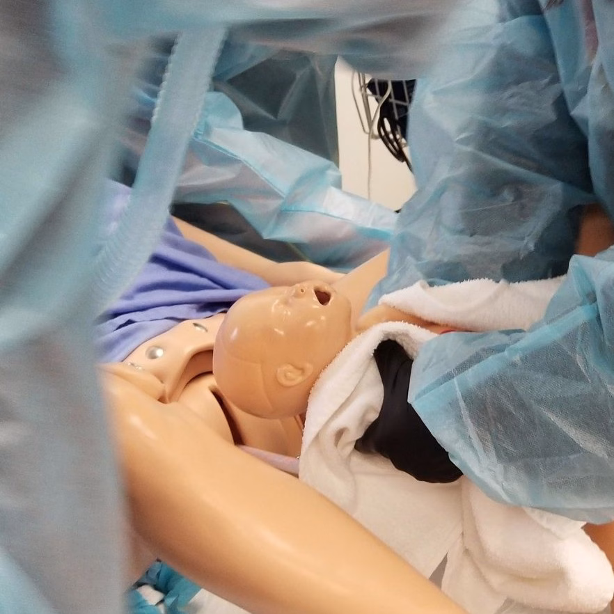 EMT students practice a birthing scenario with mannequins